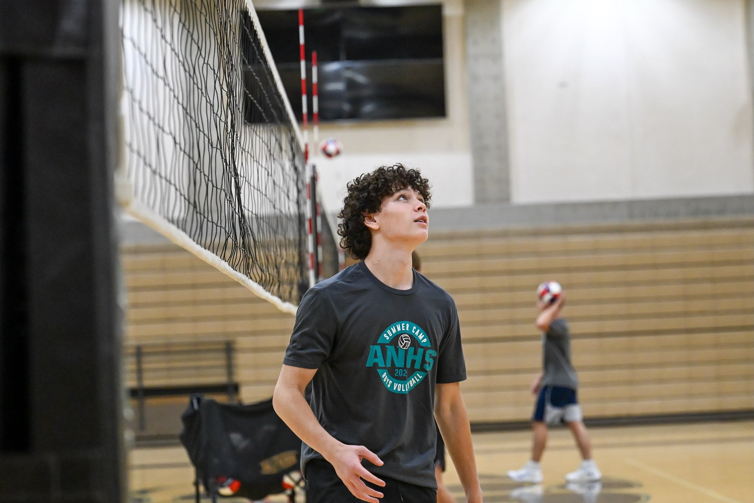 A player in an ANHS camp shirt tracks the ball overhead