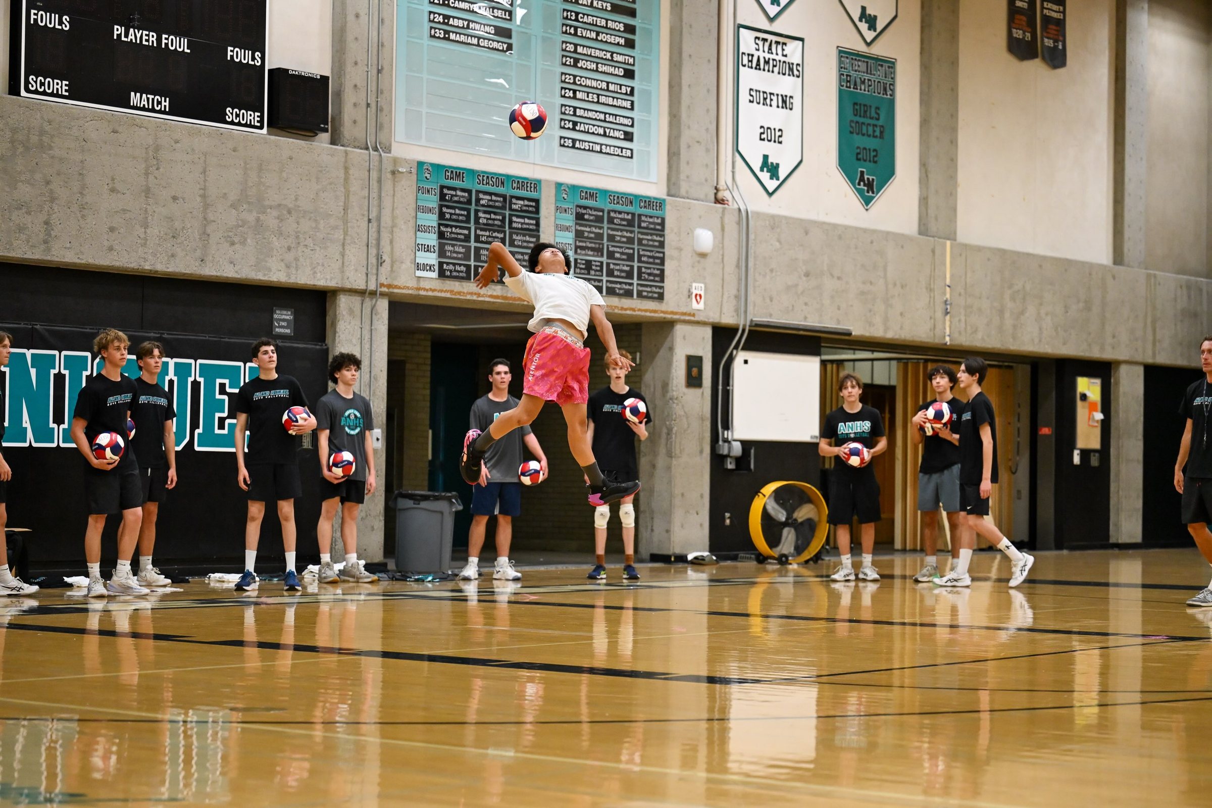 A player serves in front of the Niguel wall as the group lines up behind