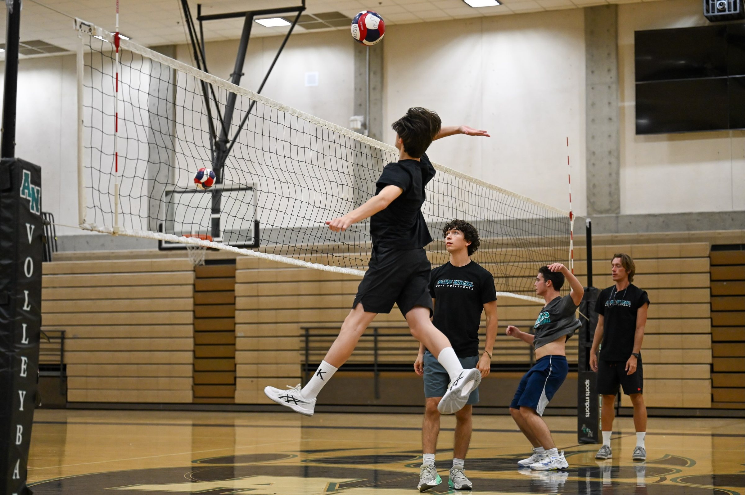 A player at full extension swinging over the net at summer camp
