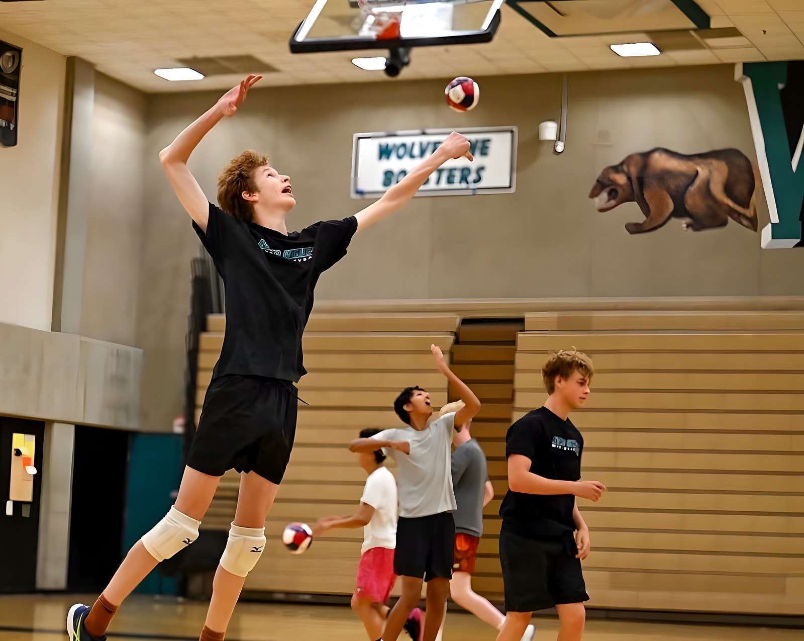A Wolverine player tosses for a jump serve under the Wolverine Boosters sign
